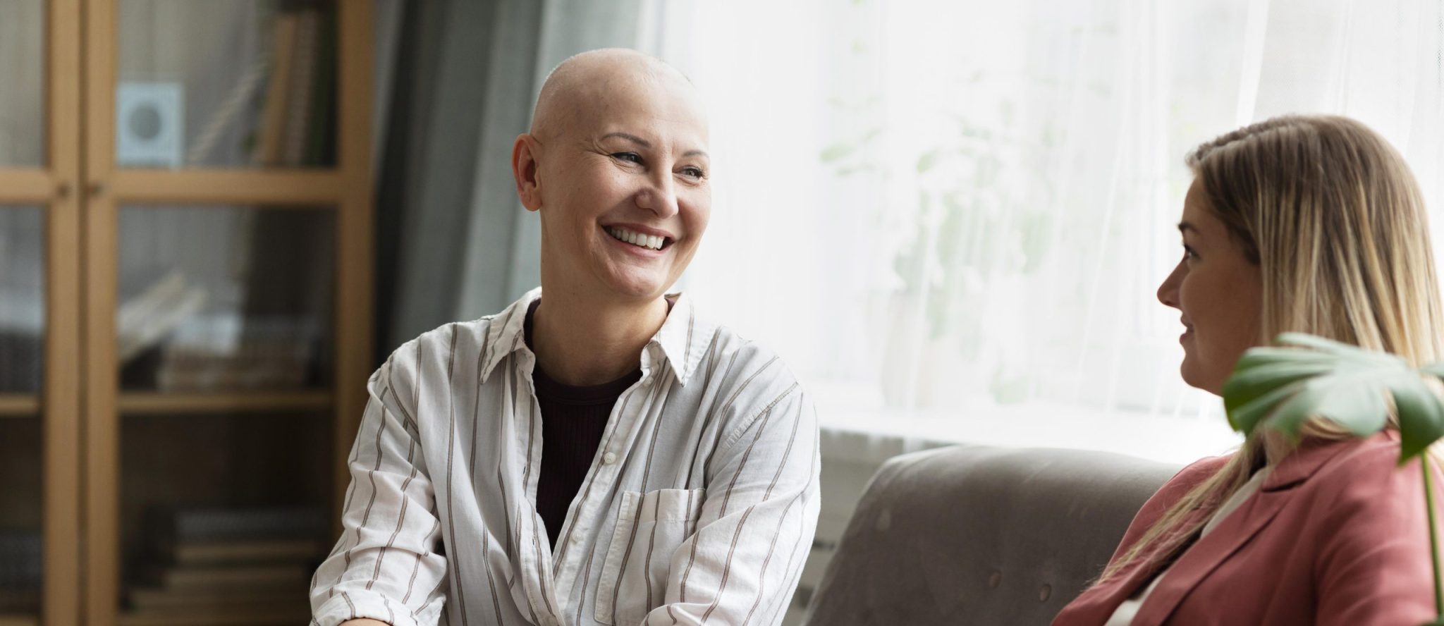 Cancer patient smiling with friend on the couch